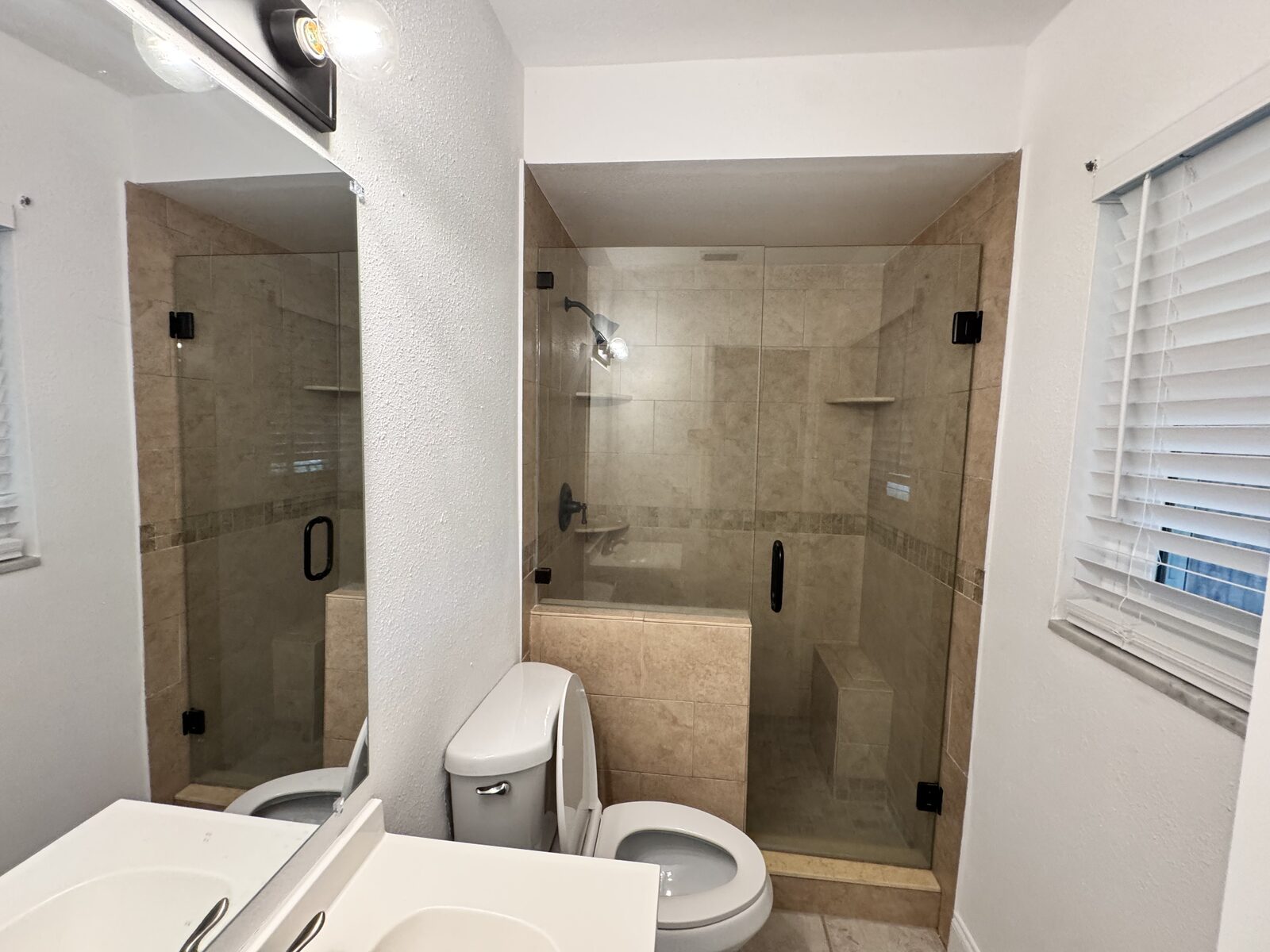 Bathroom with double vanity and glass-enclosed tiled shower