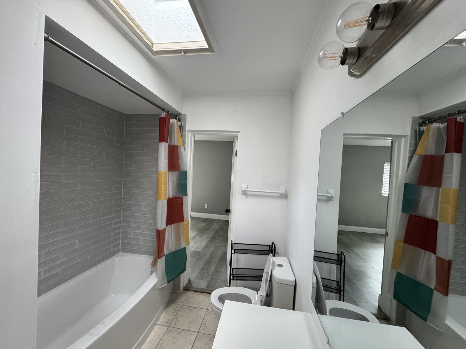 Full bathroom with tub, subway tile surround and skylight